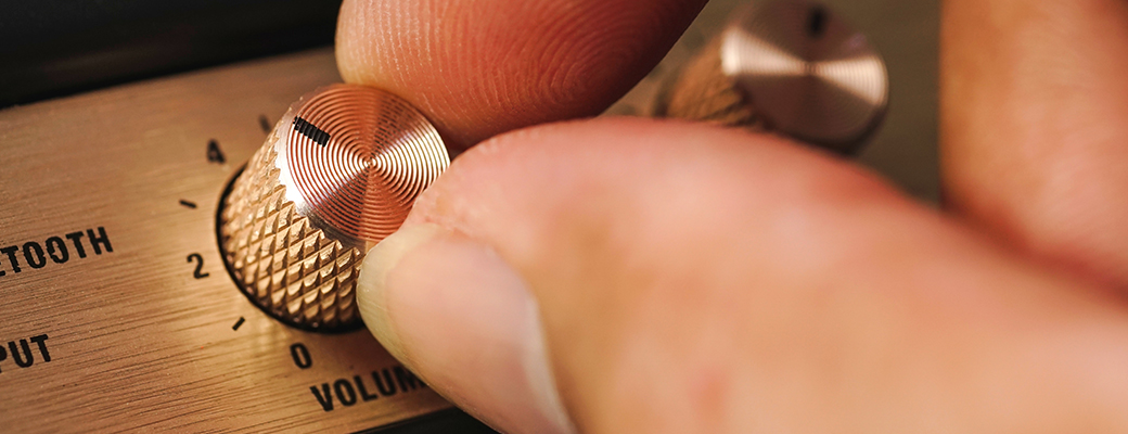 Image of hand turning the volume knob on an electronic device